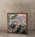 "Return to Self" abstract art print by Alyce McCann in a wooden box frame, leaning against a stone wall — pink, sage green and blue-grey floral forms