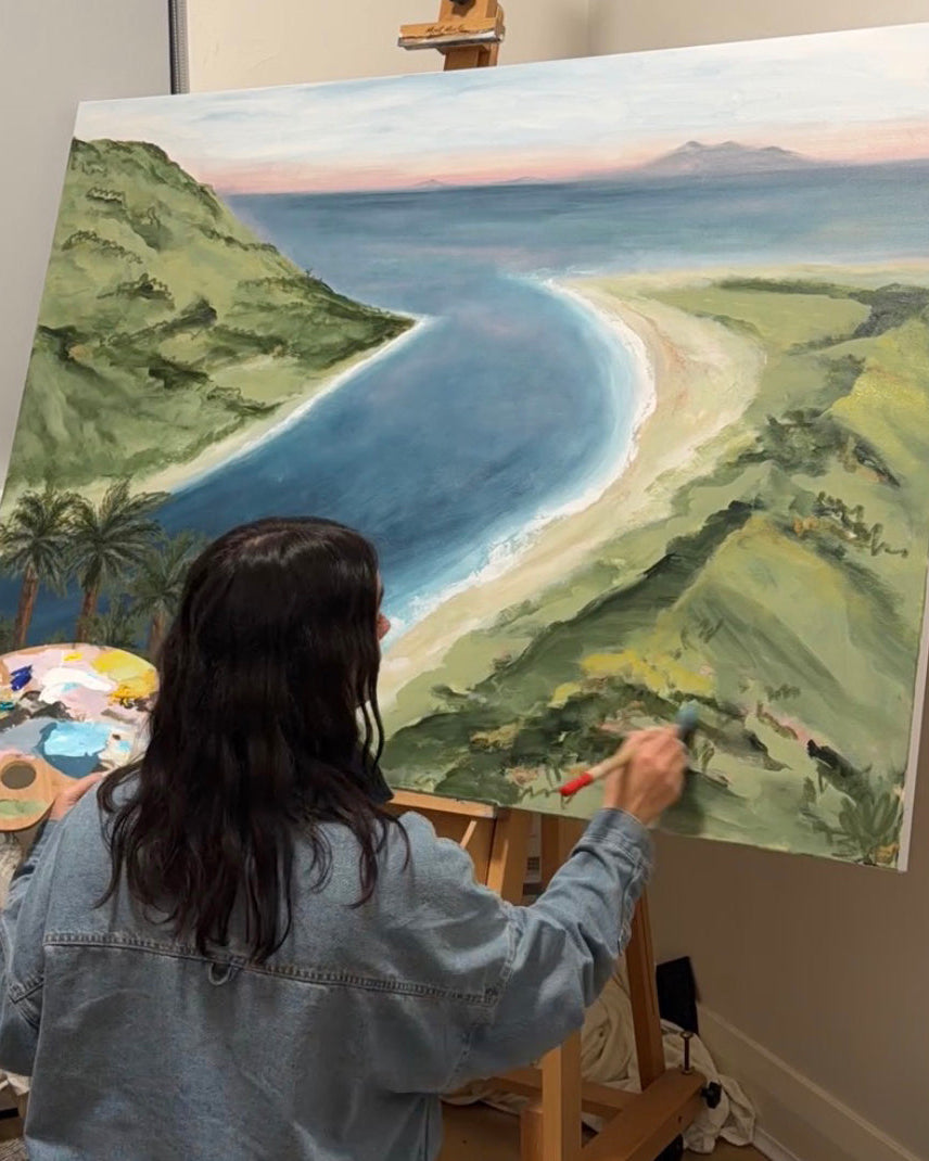 Ally McCann painting an original coastal landscape artwork on canvas.